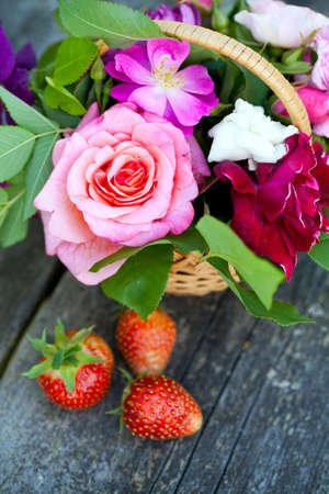 basket with roses and strawberries on garden table on a beautiful summer dayの写真素材