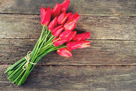bunch of red tulips on wooden surfaceの写真素材