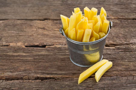 chopped potato in a bucket on wooden tableの写真素材