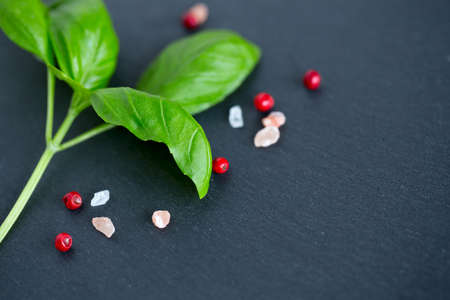 basil and pink peppercorns on black background