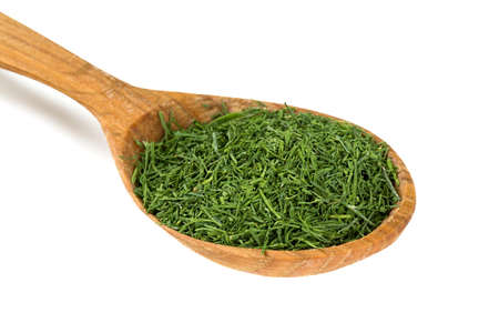 dried dill in a wooden spoon isolatedの写真素材
