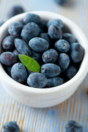 Honeysuckle berries in bowl on wooden surfaceの写真素材