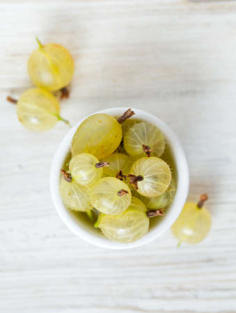 gooseberries in a bowl on wooden surfaceの写真素材