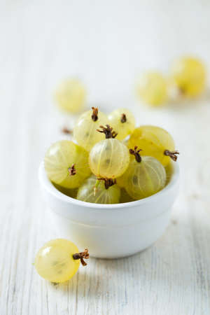 gooseberries in a bowl on wooden surfaceの写真素材