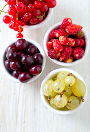 summer berries in a bowl on wooden surfaceの写真素材