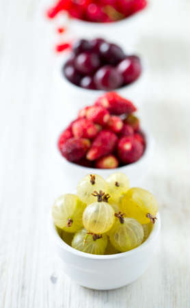 summer berries in a bowl on wooden surfaceの写真素材