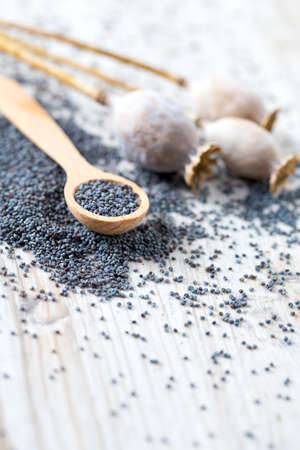 poppy seeds in a wooden spoon on wooden surfaceの写真素材