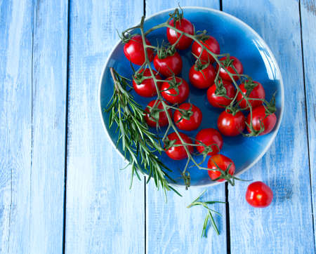 tomatoes and rosemary on wooden surfaceの写真素材