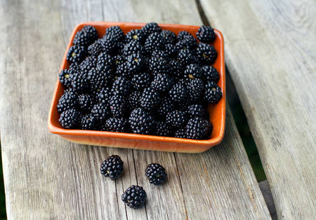 blackberries in a bowl on wooden surface
