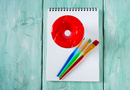 colorful paintbrushes and notebook on wooden surfaceの写真素材