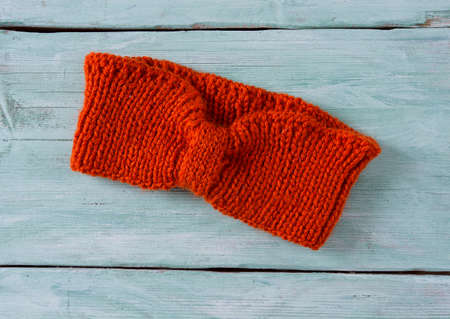 orange hand knitted headband on wooden surface