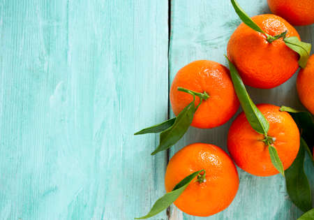 tangerines with green leaves on turquoise wooden backgroundの写真素材