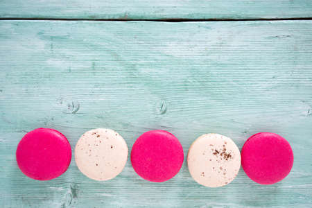 raspberry and vanilla macaroons on turquoise wooden surfaceの写真素材