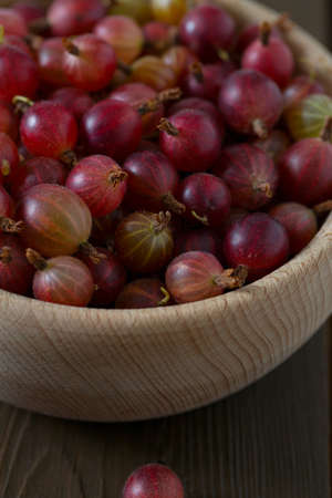 Red gooseberry in a bowl on wooden surfaceの写真素材
