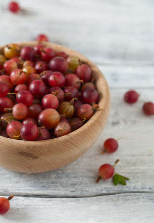Red gooseberry in a bowl on wooden surfaceの写真素材