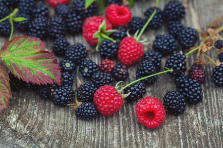 fresh raspberries and blackberries on eustic wooden surface