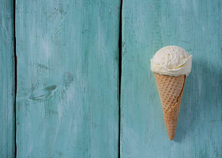 single vanilla ice cream in waffle scone on turquoise surfaceの写真素材
