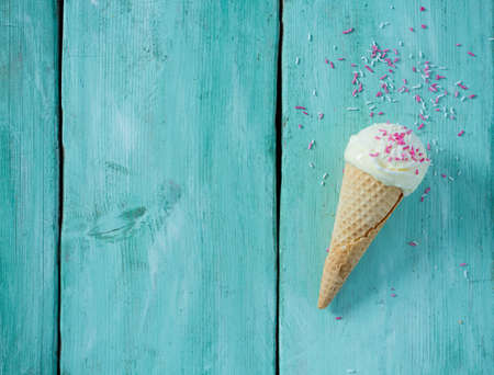 single vanilla ice cream in waffle scone on turquoise surfaceの写真素材