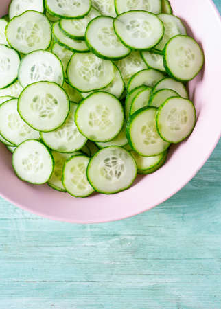 cucumbers in a bowl on turquoise surfaceの写真素材