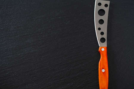 cheese knife with a wooden handle over black