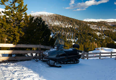 black snowmobile on a sunny day in mountains