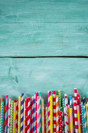 multicolored paper straws on turquoise wooden background