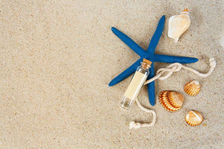 message in a bottle, sea shells and pebbles on sandの写真素材