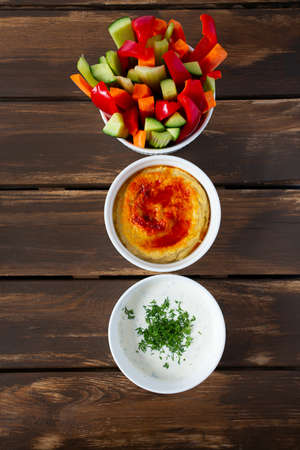 fresh vegetables, saur cream dip and hummus isolated on white