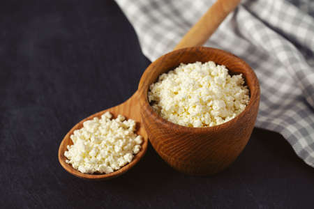 cottage cheese in a wooden bowl on black stone surface