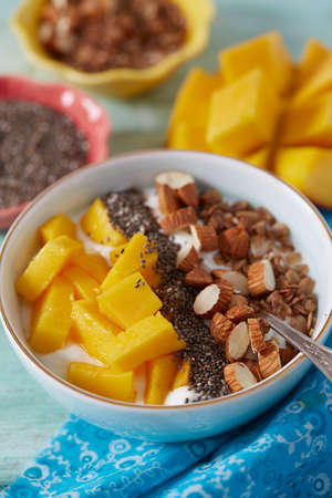 mango and greek yoghurt with seeds and nuts on wooden surfaceの写真素材