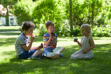 kids are eating sweets in a parkの写真素材