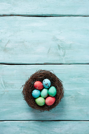 Easter eggs in a nest on a turquoise wooden background