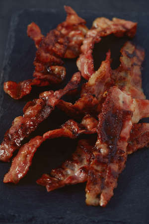 fried bacon on black surfaceの写真素材