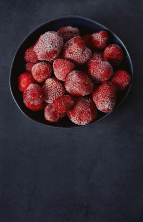 Frozen strawberries on a black background. Berries are being preserved for winter.の写真素材