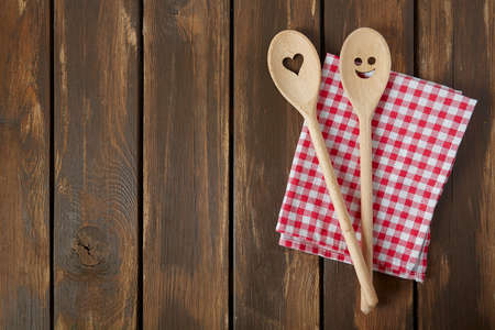 Two wooden spoons on brown wooden surface. Cooking concept. Spoons are with a smile and heart on it.の写真素材