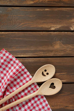 Two wooden spoons on brown wooden surface. Cooking concept. Spoons are with a smile and heart on it.の写真素材