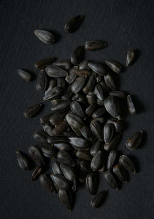 black sun flower seeds on black stone surfaceの写真素材