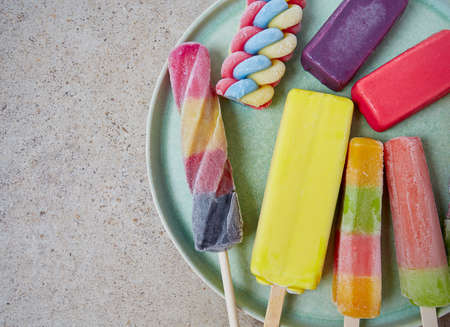 colorful popsicles on grey stone surface
