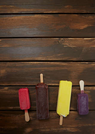colorful popsicles on brown wooden surfaceの写真素材
