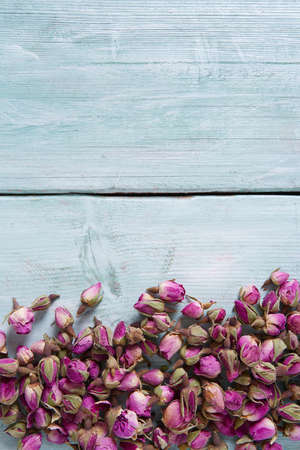 dried rose buds on turquoise wooden surfaceの写真素材