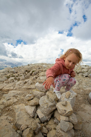 cute girl is building a stone pyramid in mountainsの写真素材