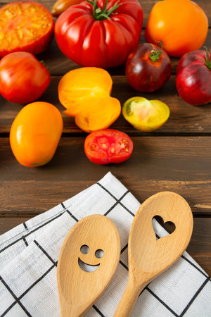 Collection of ripe fresh tomatoes and smiling spoons on brown wooden surface. Cooking and gardening concept. Food backgrounds.の写真素材