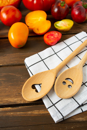 Collection of ripe fresh tomatoes and smiling spoons on brown wooden surface. Cooking and gardening concept. Food backgrounds.の写真素材