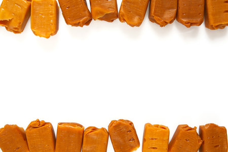 Soft caramel candies. Butterscotch toffee pieces isolated on white background.の写真素材