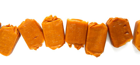Soft caramel candies. Butterscotch toffee pieces isolated on white background.の写真素材