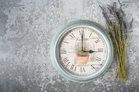 Beautiful vintage clock with lavender flowers on grey stone surfaceの写真素材