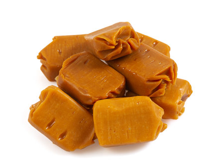 Soft caramel candies. Butterscotch toffee pieces isolated on white background.の写真素材