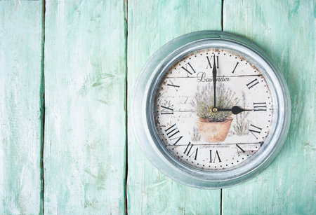Beautiful vintage clock with lavender flowers on turquoise wooden surface.の写真素材