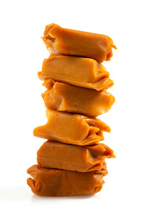 Stack of oft caramel candies. Butterscotch toffee pieces isolated on white background.の写真素材