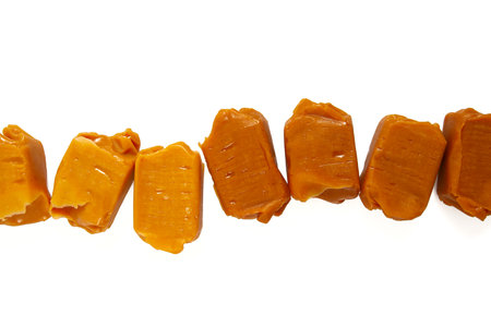Soft caramel candies. Butterscotch toffee pieces isolated on white background. Top view.の写真素材